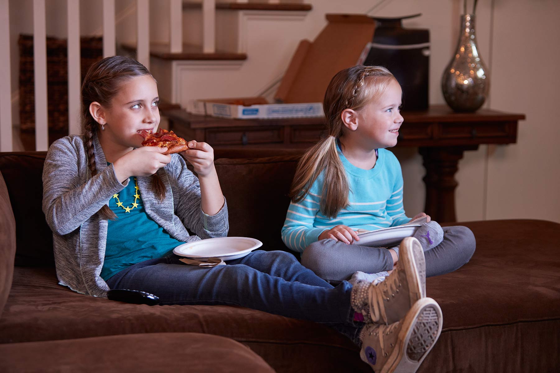 Girls watching TV eating pizza on couch